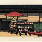 estampe japonaise de Nishijima, une boutique de souvenirs japonais avec Daruma, éventails, céramique... sous un parasol rouge