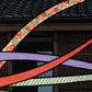 estampe japonaise contemporaine obi au vent devant facade en bois de maison traditionnelle japonaise, gros plan sur les ceintures colorées
