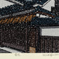 estampe japonaise neige tombant la nuit sur maison traditionnelle japonaise, signature de l'artiste Nishijima