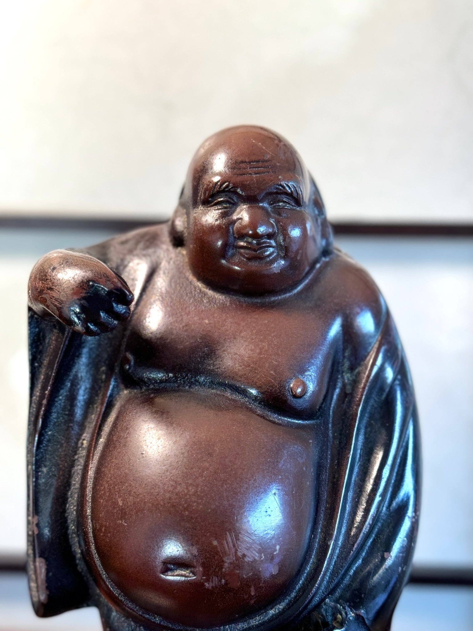 statuette en bronze cuivré de Hotei, dieu du bonheur, gros plan sur le torse nu