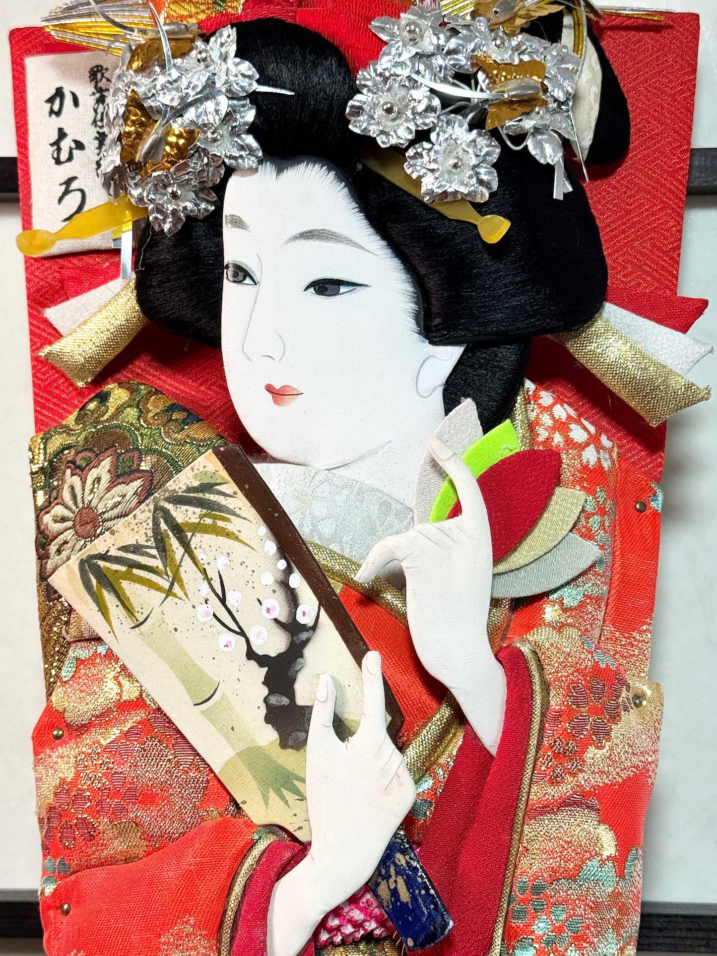 raquette décorative japonaise hagoita, femme tenant une hagoita miniature, motif bambou et prunier en fleur, gros plan sur le visage