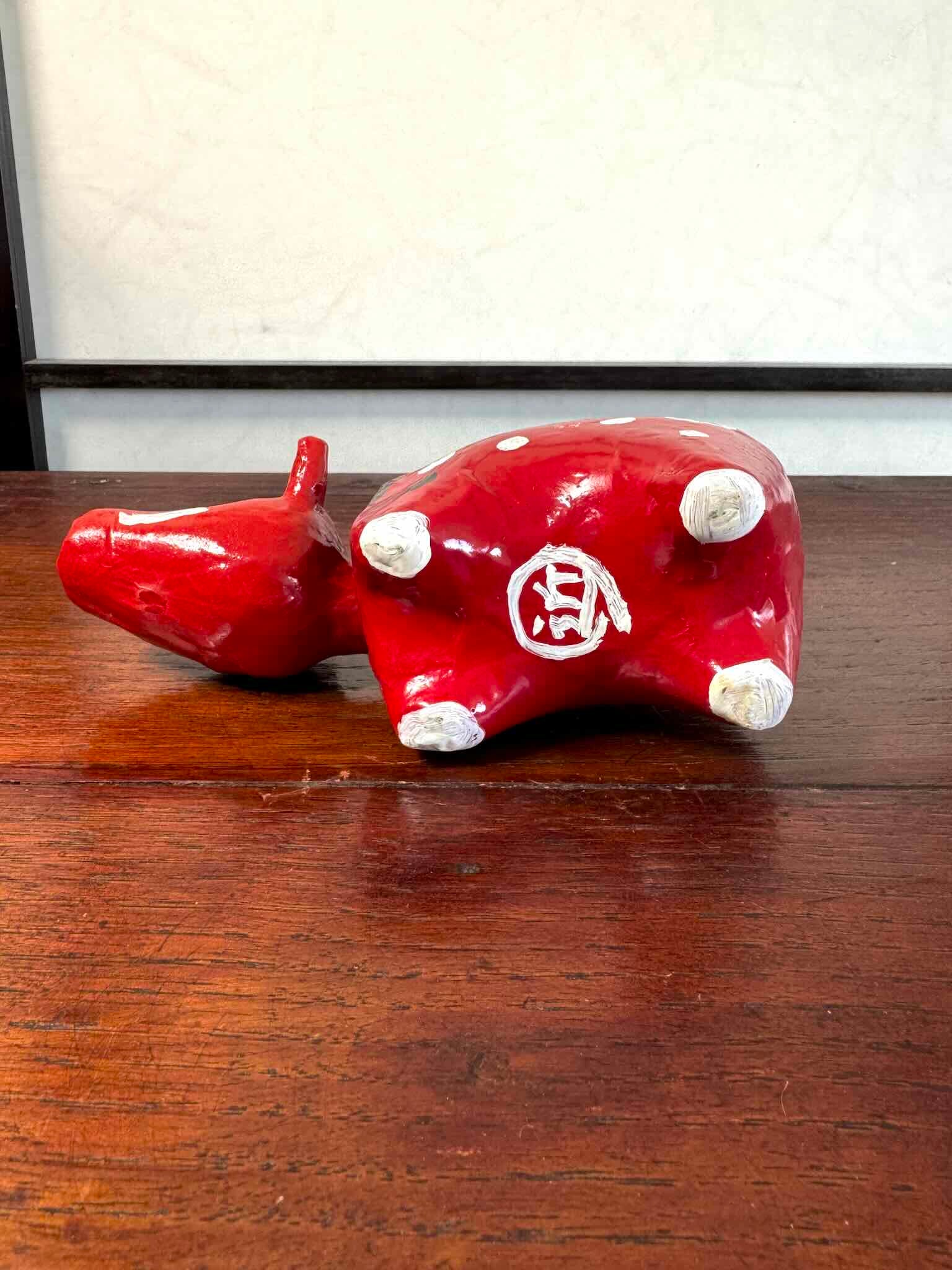Akabeko japonais ancien rouge à pois blancs en papier mâché peint à la main, vu de dessous le sceau de l'artisan