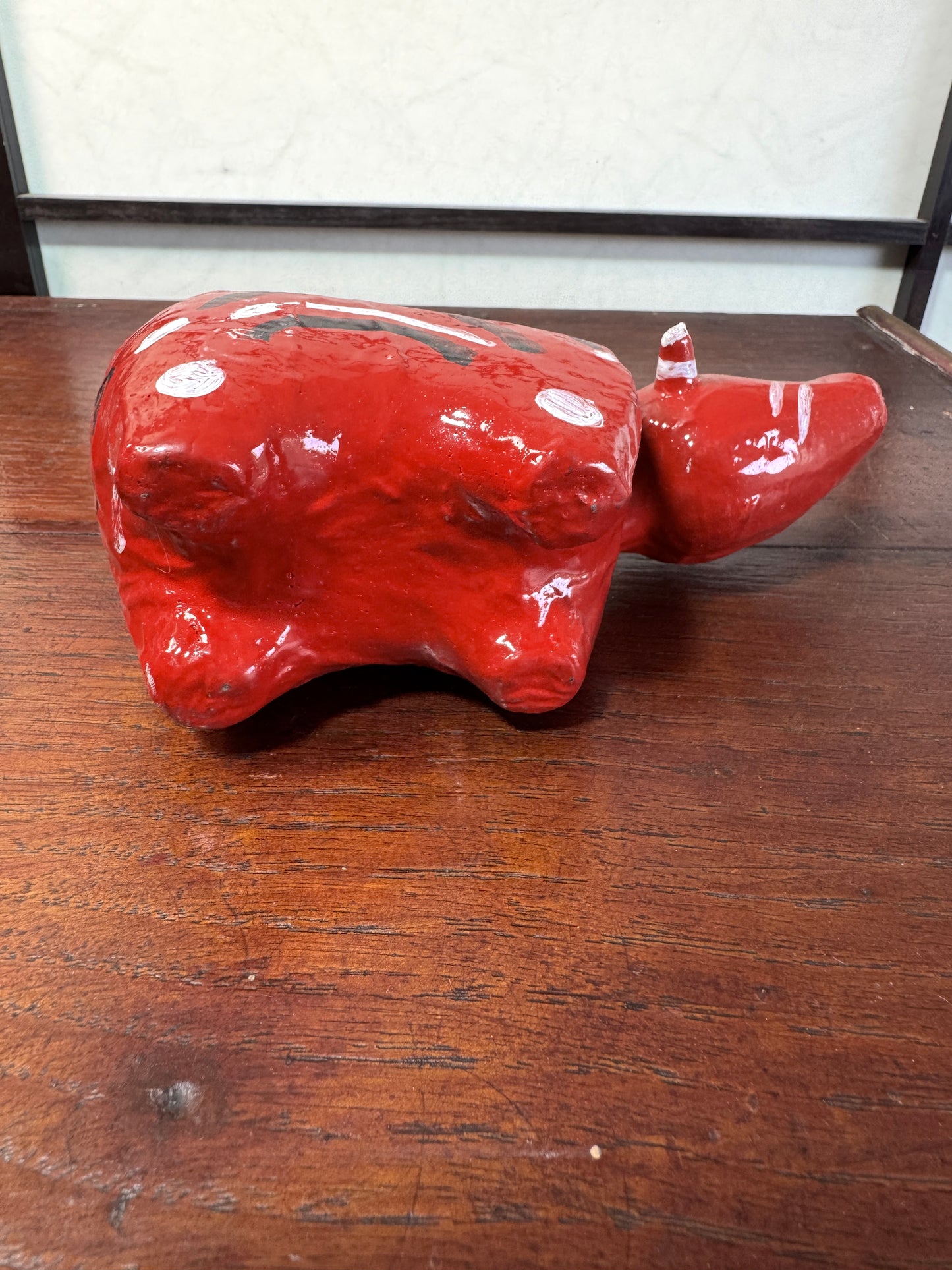 Akabeko japonais ancien rouge en papier mâché peint à la main, vu de dessous