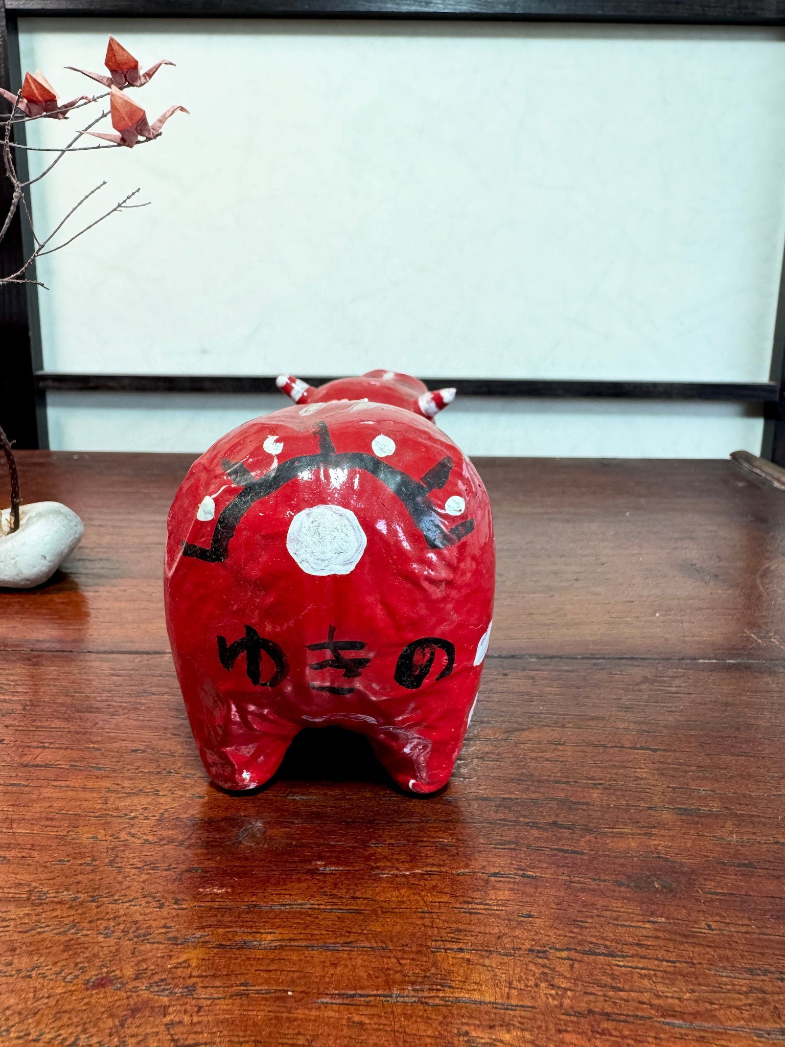 Akabeko japonais ancien rouge en papier mâché peint à la main, vu de dos la signature