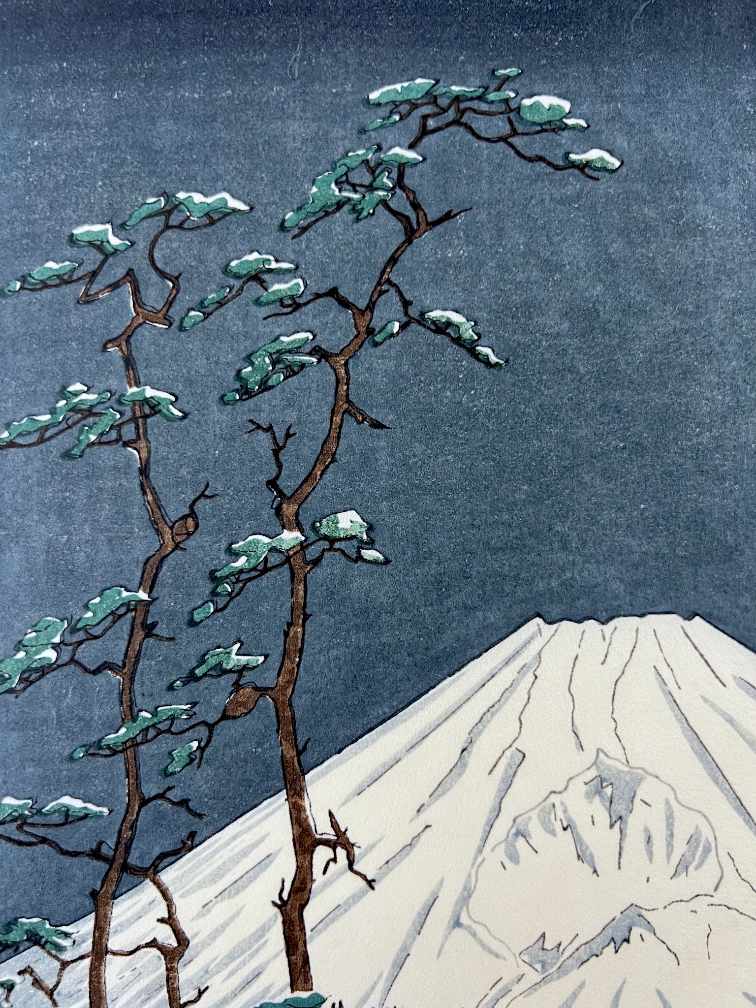 estampe japonaise Mont Fuji blanc dans le gris bleu sombre de la nuit, arbres bleus au premier plan, les pins