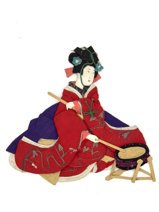 Okiyage japonais représentant une femme jouant du tambour, vêtue d’un kimono rouge brodé, coiffée de fleurs et rubans, réalisée en tissu 