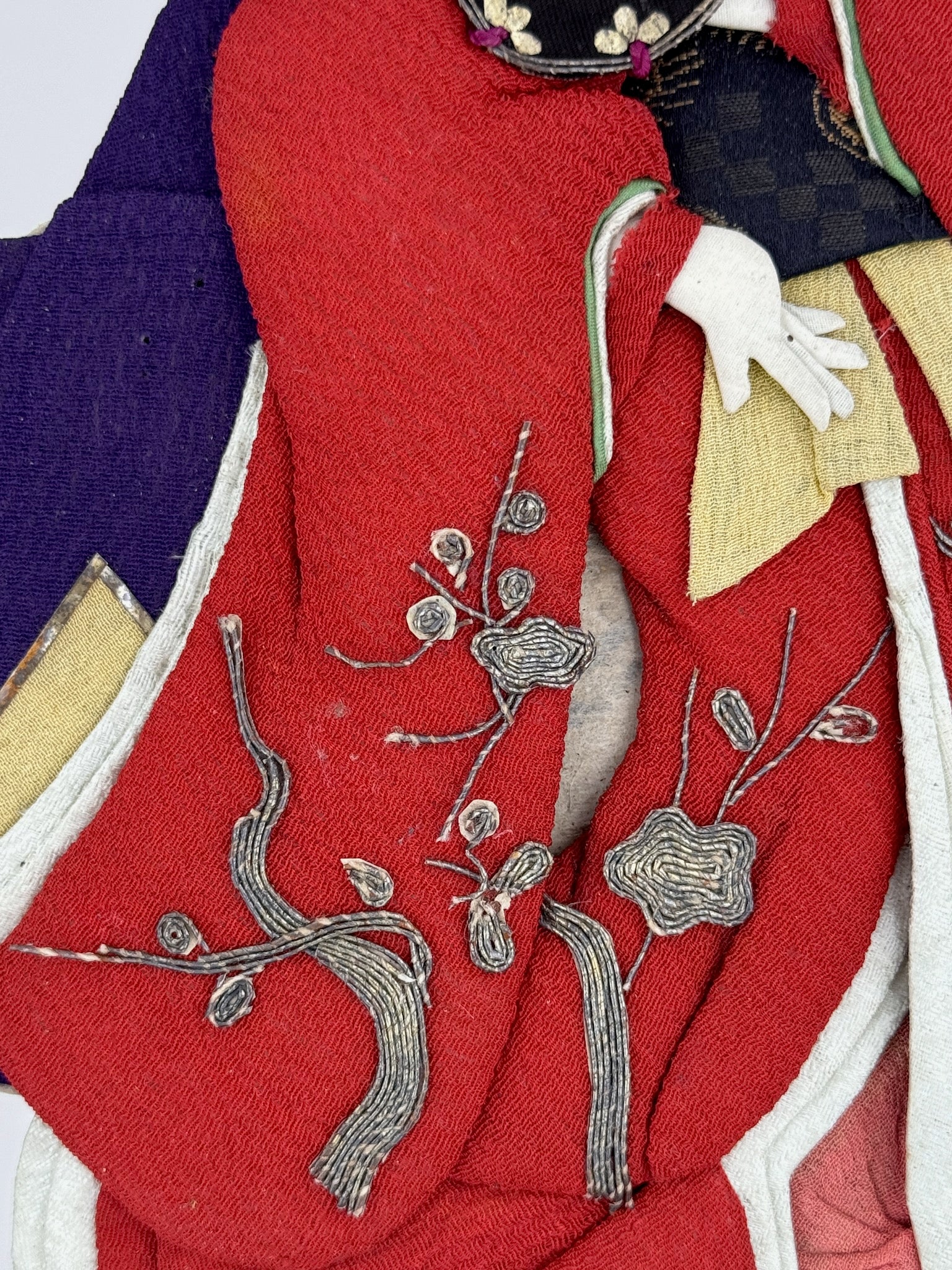 Okiyage japonais représentant une femme en kimono rouge brodé tenant un tambour tsuzumi, réalisée en tissu ancien avec coiffure et accessoires traditionnels, gros plan sur les broderies en fils d'argent
