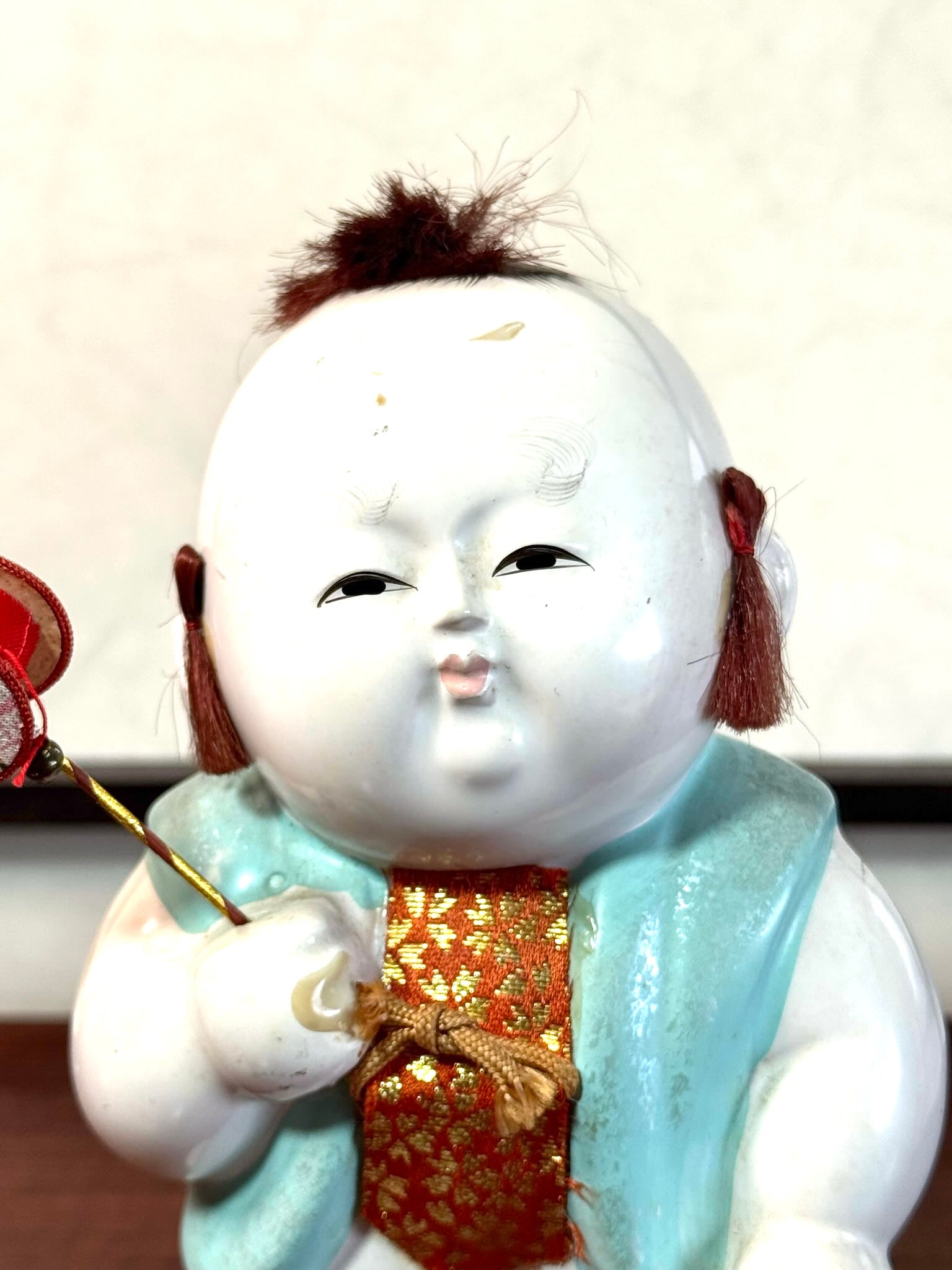 Gosho Ningyō ancien en céramique d’Hakata représentant un gosho, enfant japonais avec jouet et panier, gros plan sur le visage
