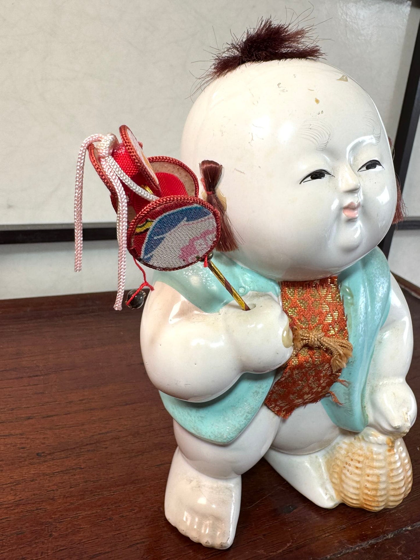 Gosho Ningyō ancien en céramique d’Hakata représentant un gosho, enfant japonais avec jouet et panier, vu de 3/4
