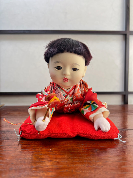 poupée japonaise traditionnelle, bébé à plat ventre sur son coussin