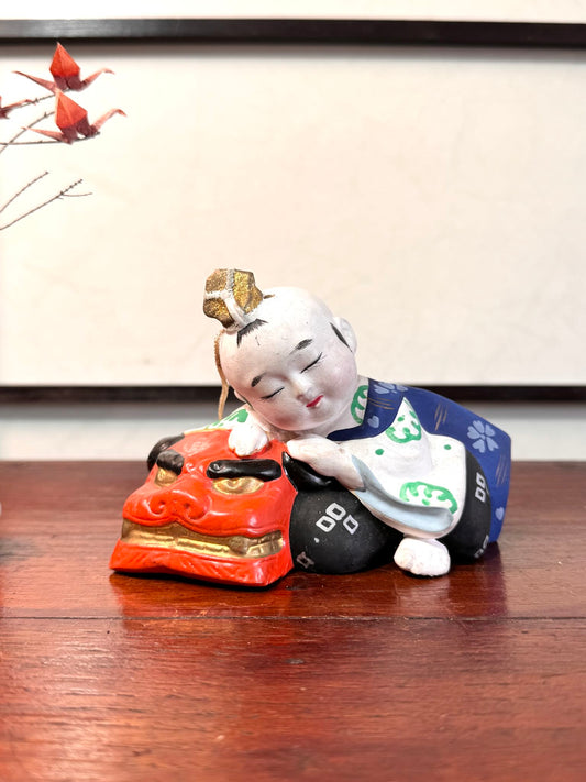 céramique japonaise,enfant endormi sur tete de lion shishi, vu de face