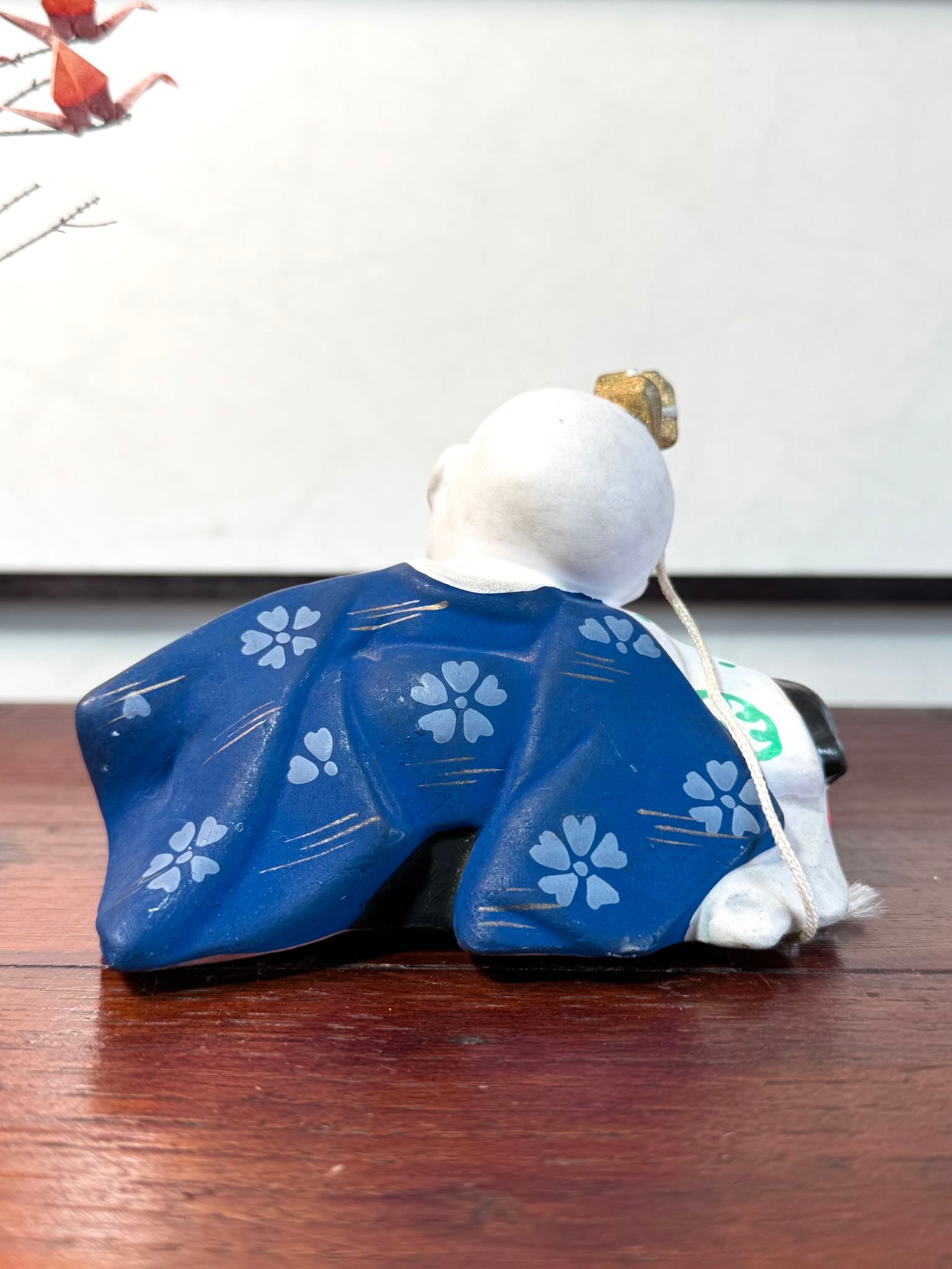 céramique japonaise,enfant endormi sur tete de lion shishi, vu de dos