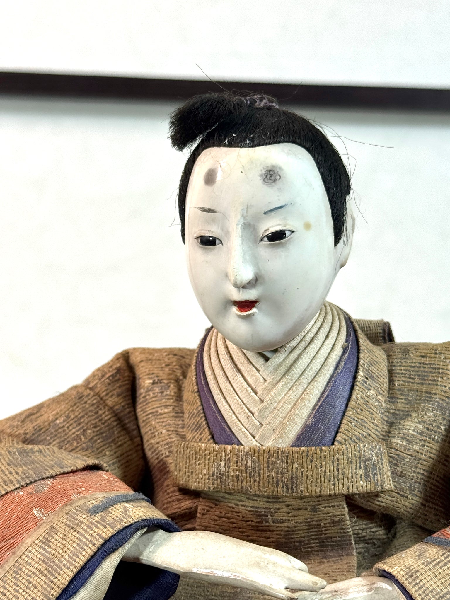 Poupée japonaise ancienne de seigneur assis en kimono , gros plan sur le visage