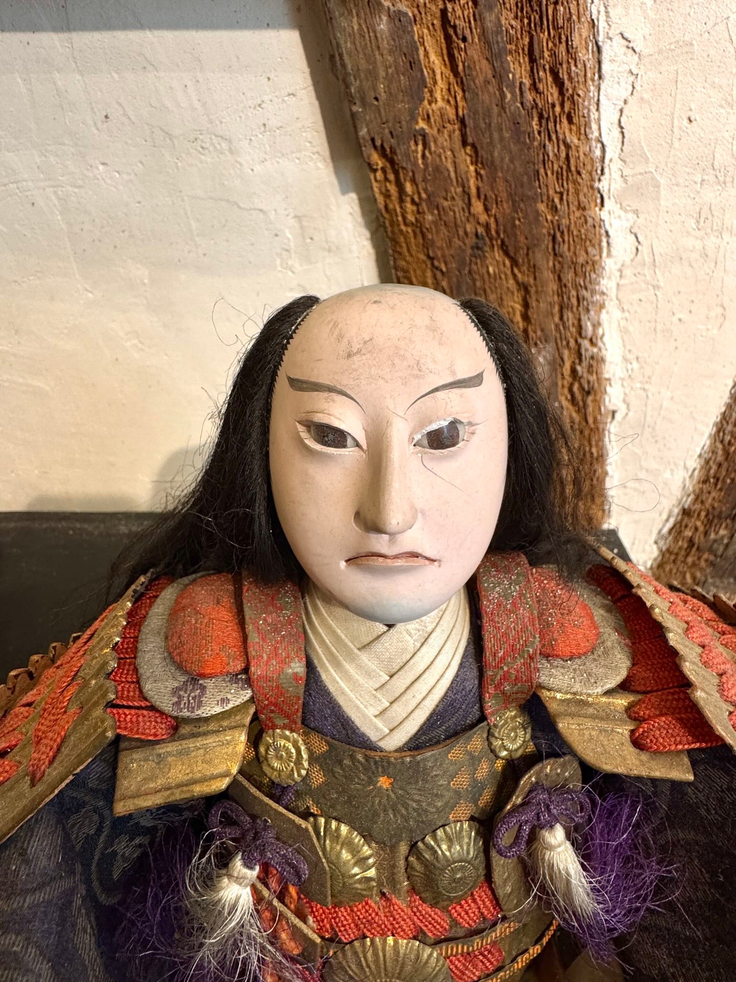Poupée japonaise ancienne samouraï en armure rouge et or traditionnelle, gros plan sur le visage