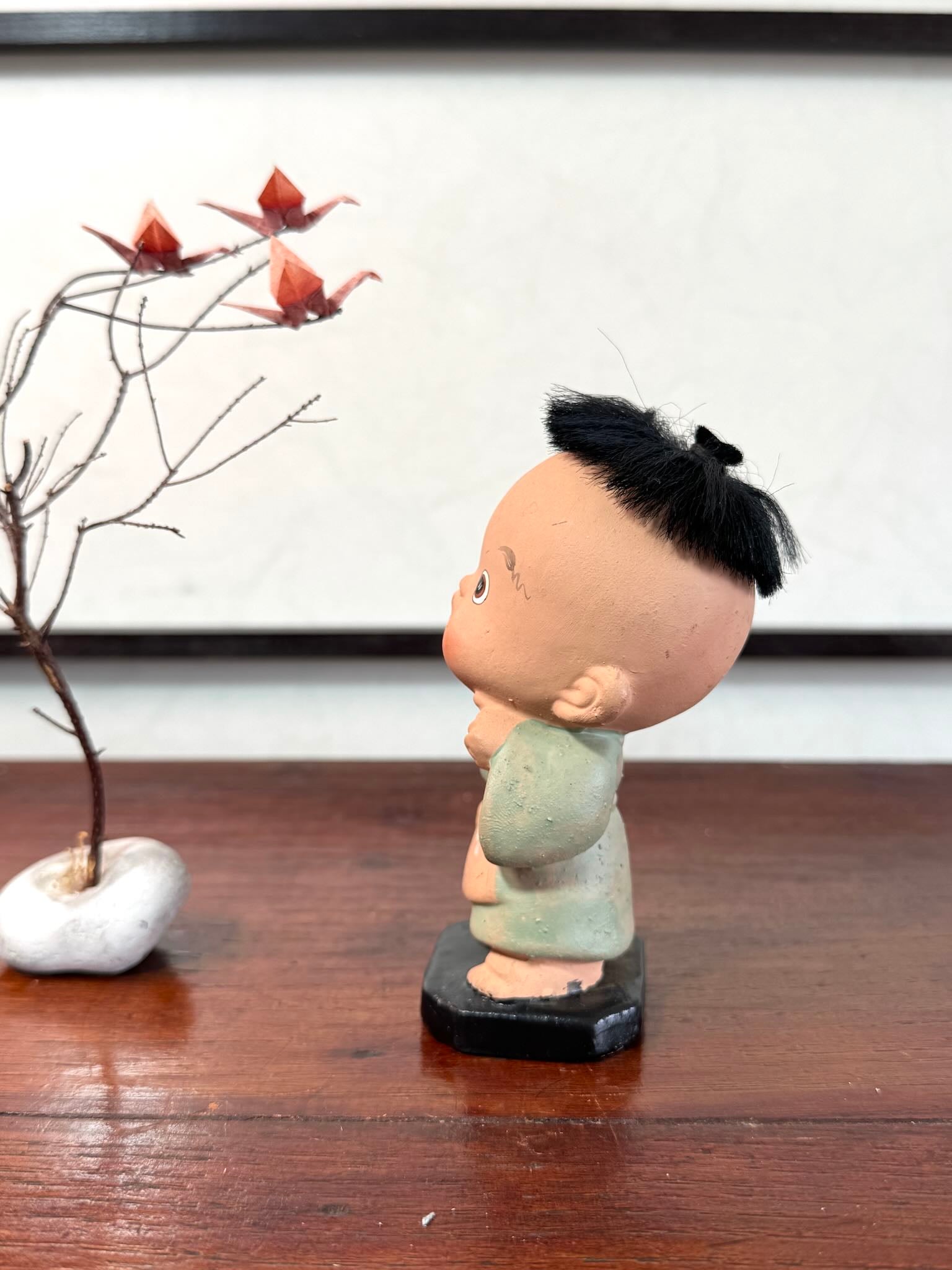 Figurine japonaise ancienne d’enfant étonné en céramique avec cheveux noirs, le profil gauche