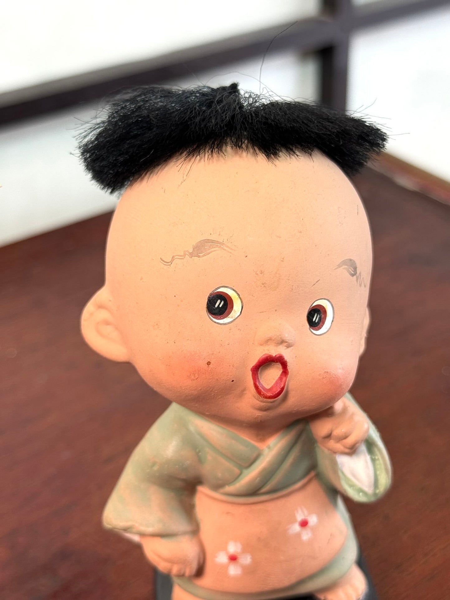 Figurine japonaise ancienne d’enfant étonné en céramique avec cheveux noirs, gros plan du visage