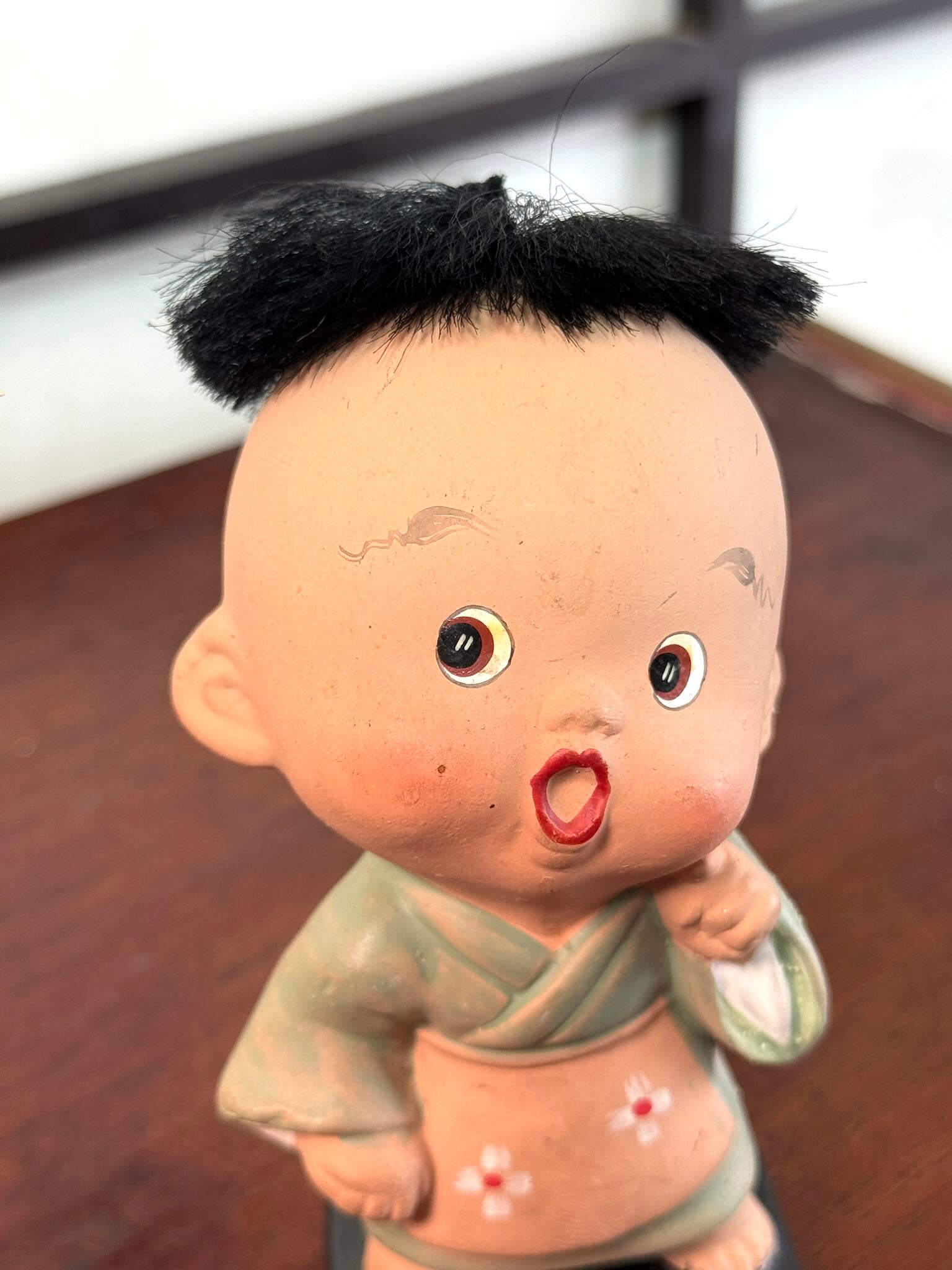 Figurine japonaise ancienne d’enfant étonné en céramique avec cheveux noirs, gros plan du visage