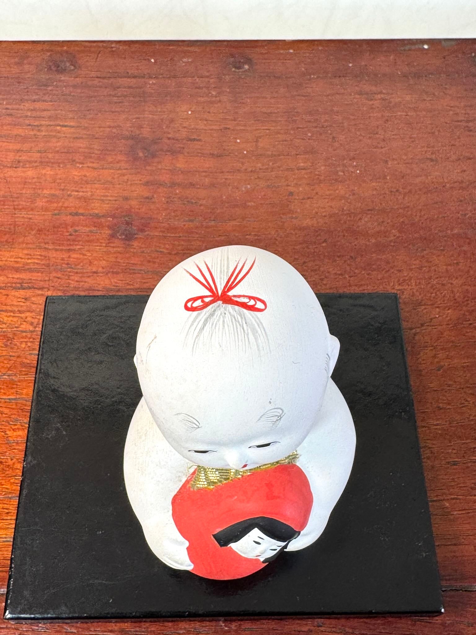 Gosho Ningyō en céramique tenant un Hime Daruma rouge japonais, vu de dessus