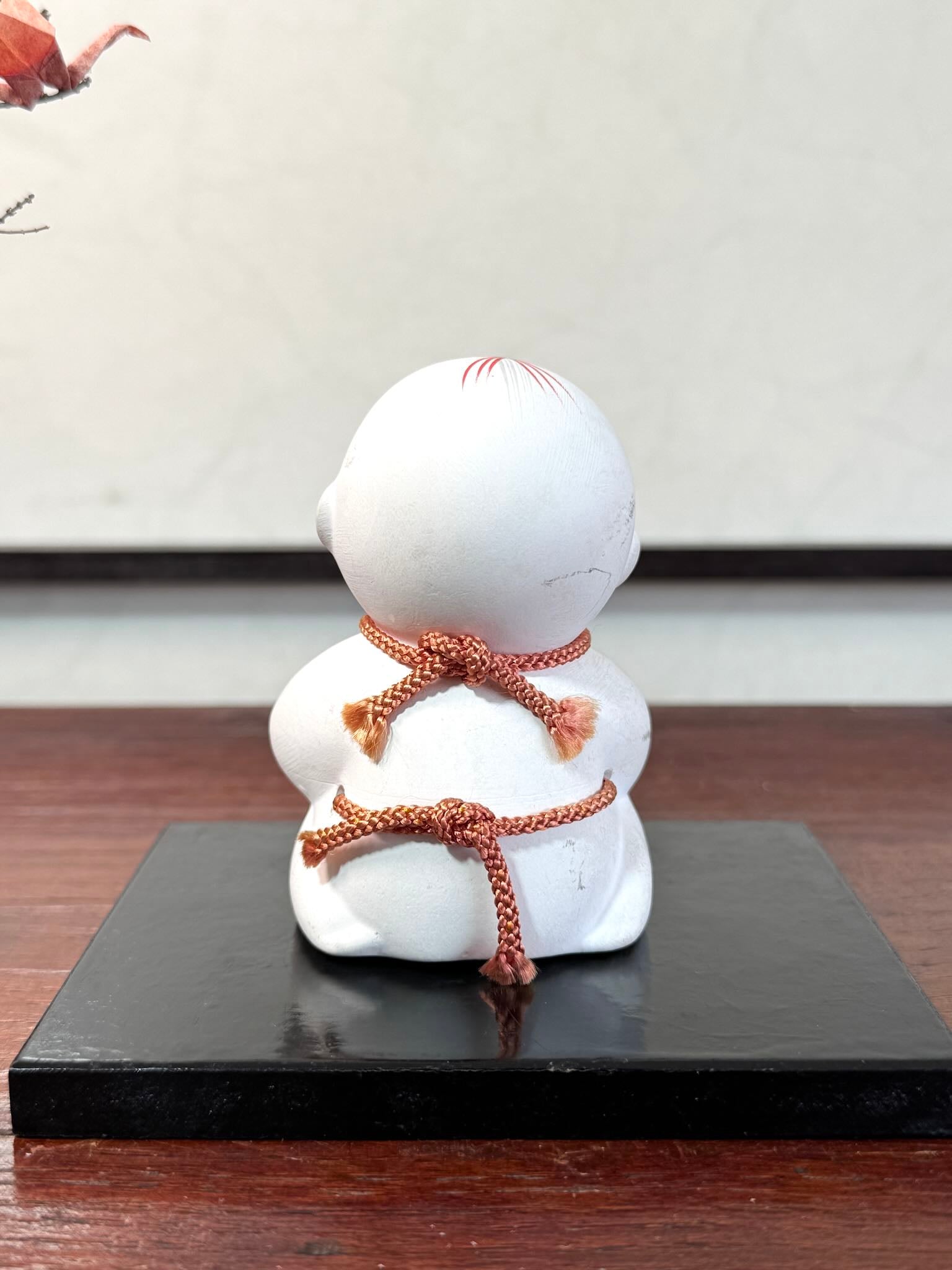 Gosho Ningyō en céramique tenant un Hime Daruma rouge japonais, vu de dos