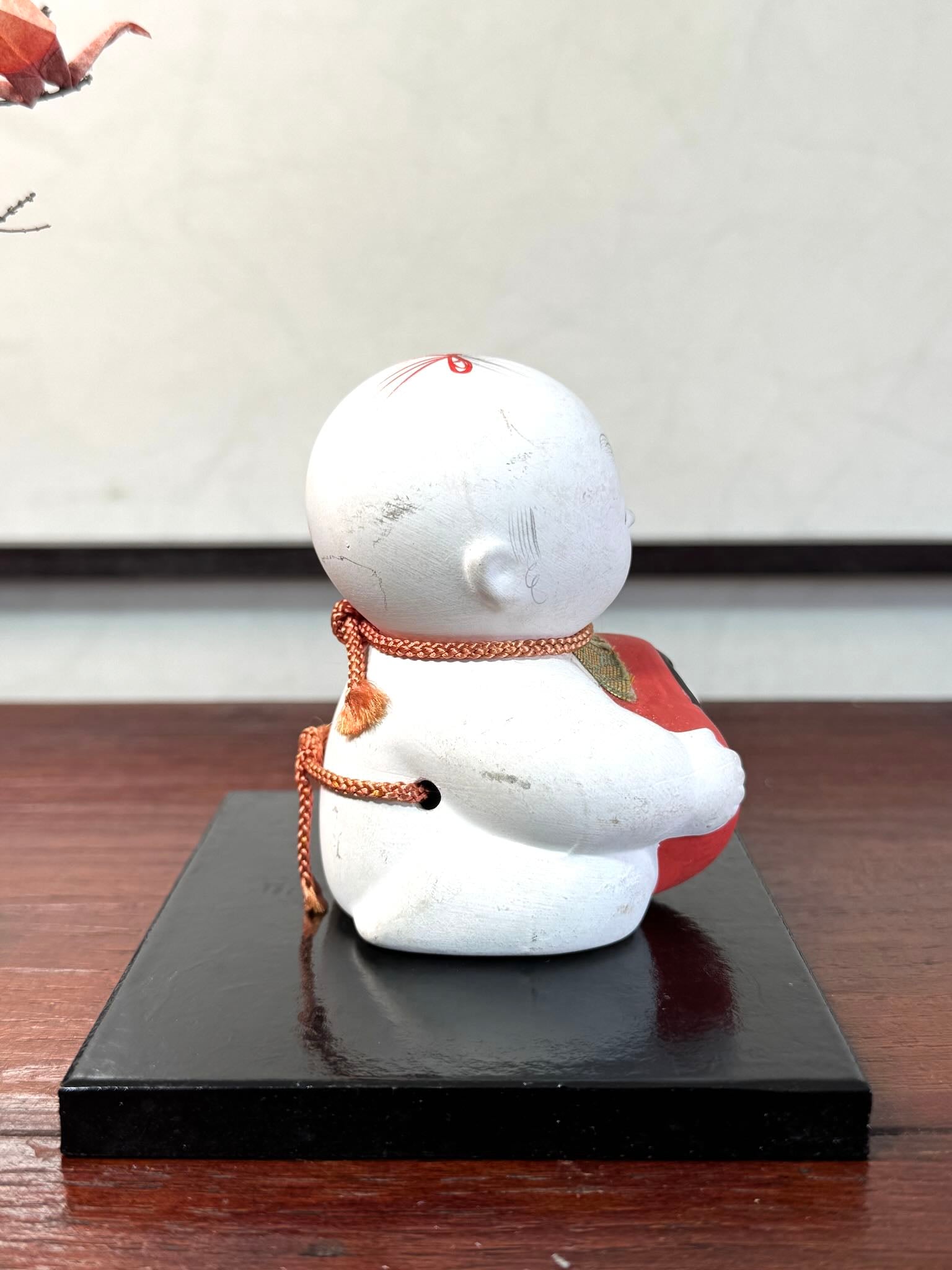 Gosho Ningyō en céramique tenant un Hime Daruma rouge japonais, le profil droit