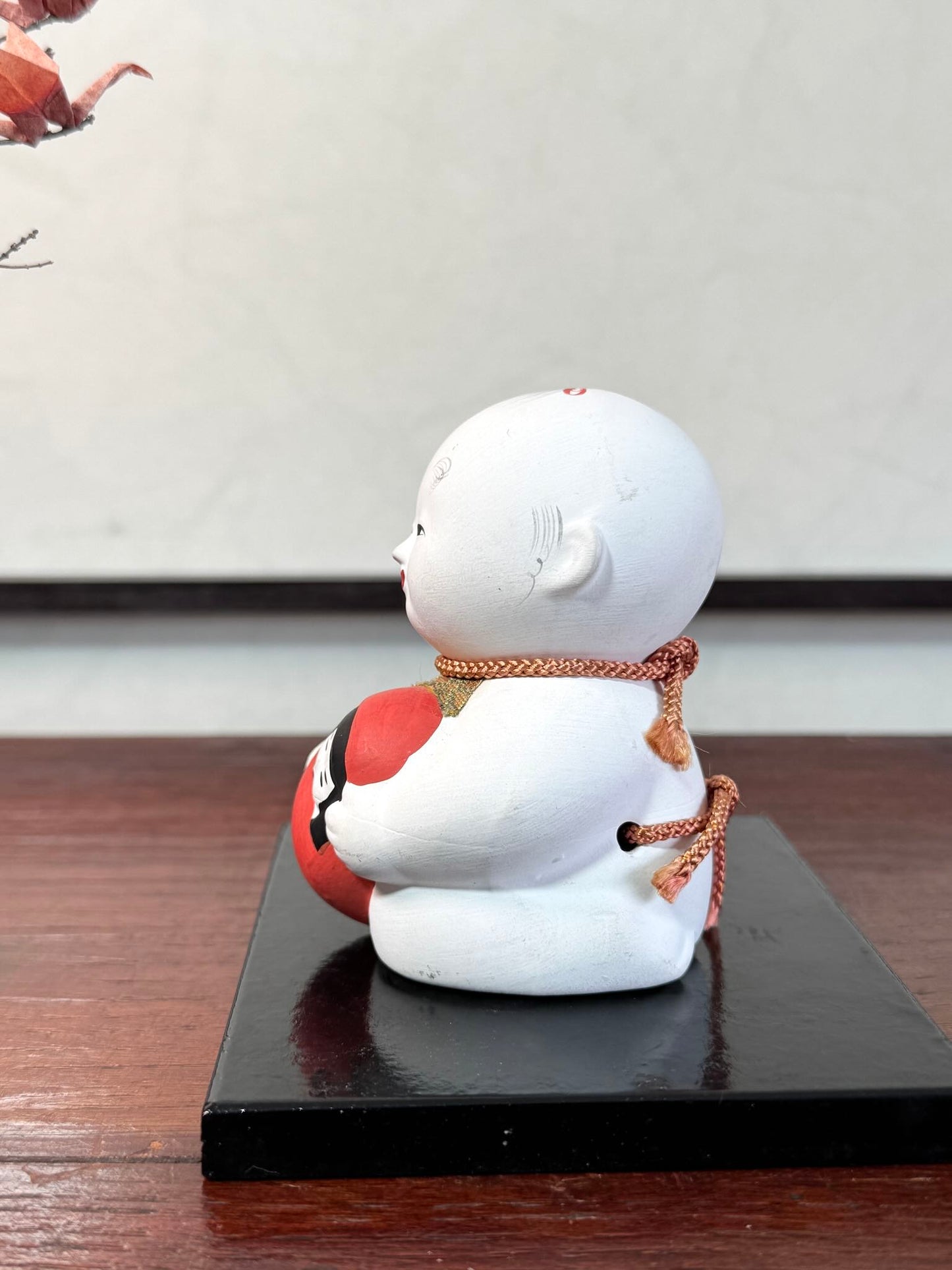 Gosho Ningyō en céramique tenant un Hime Daruma rouge japonais, le profil gauche