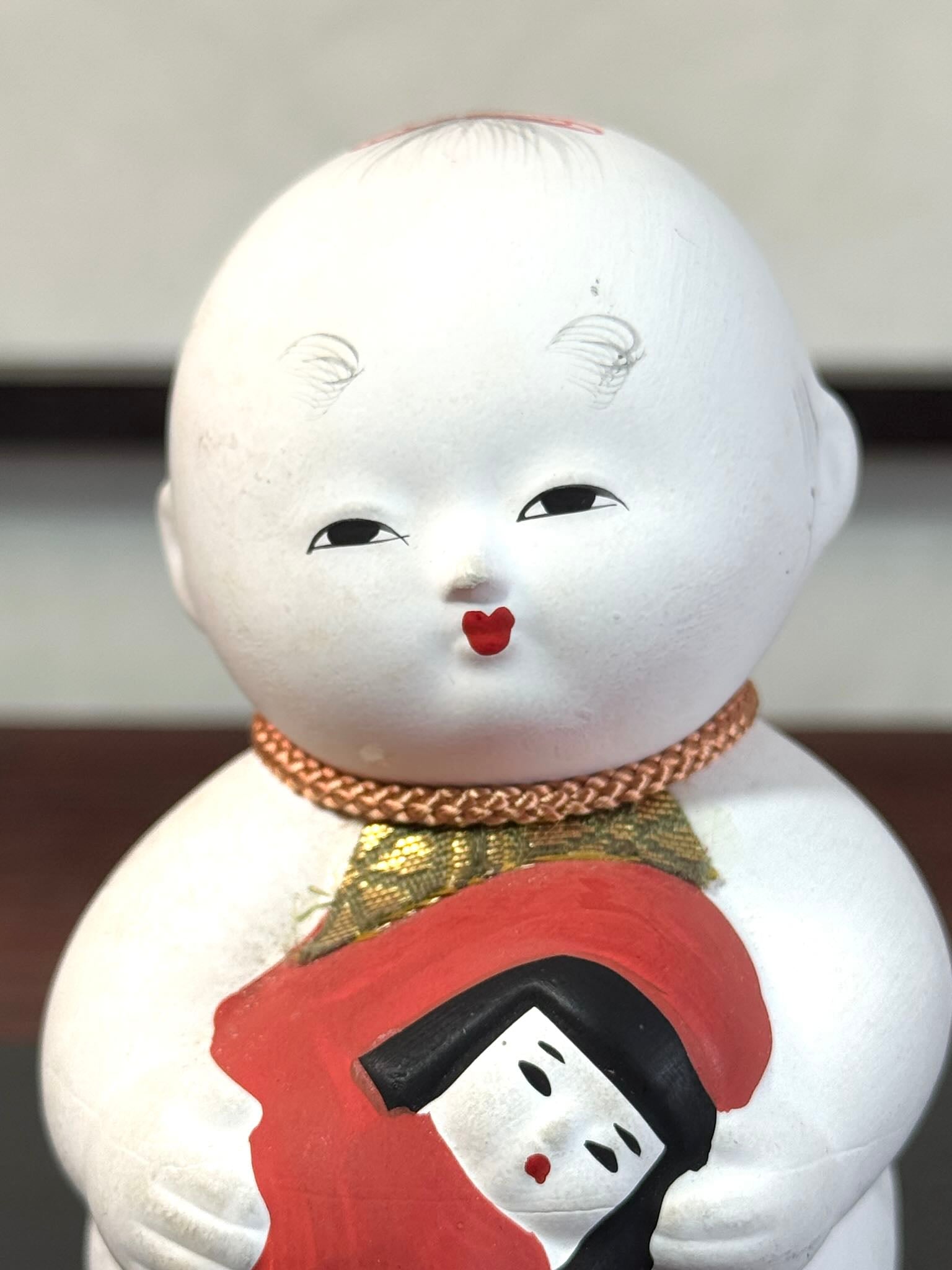 Gosho Ningyō en céramique tenant un Hime Daruma rouge japonais, gros plan sur le visage