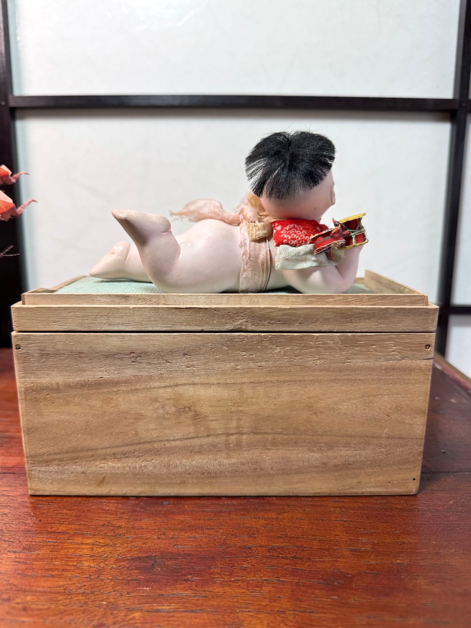 Poupée japonaise ancienne bébé couché en terre cuite sur boite en bois; profil droit