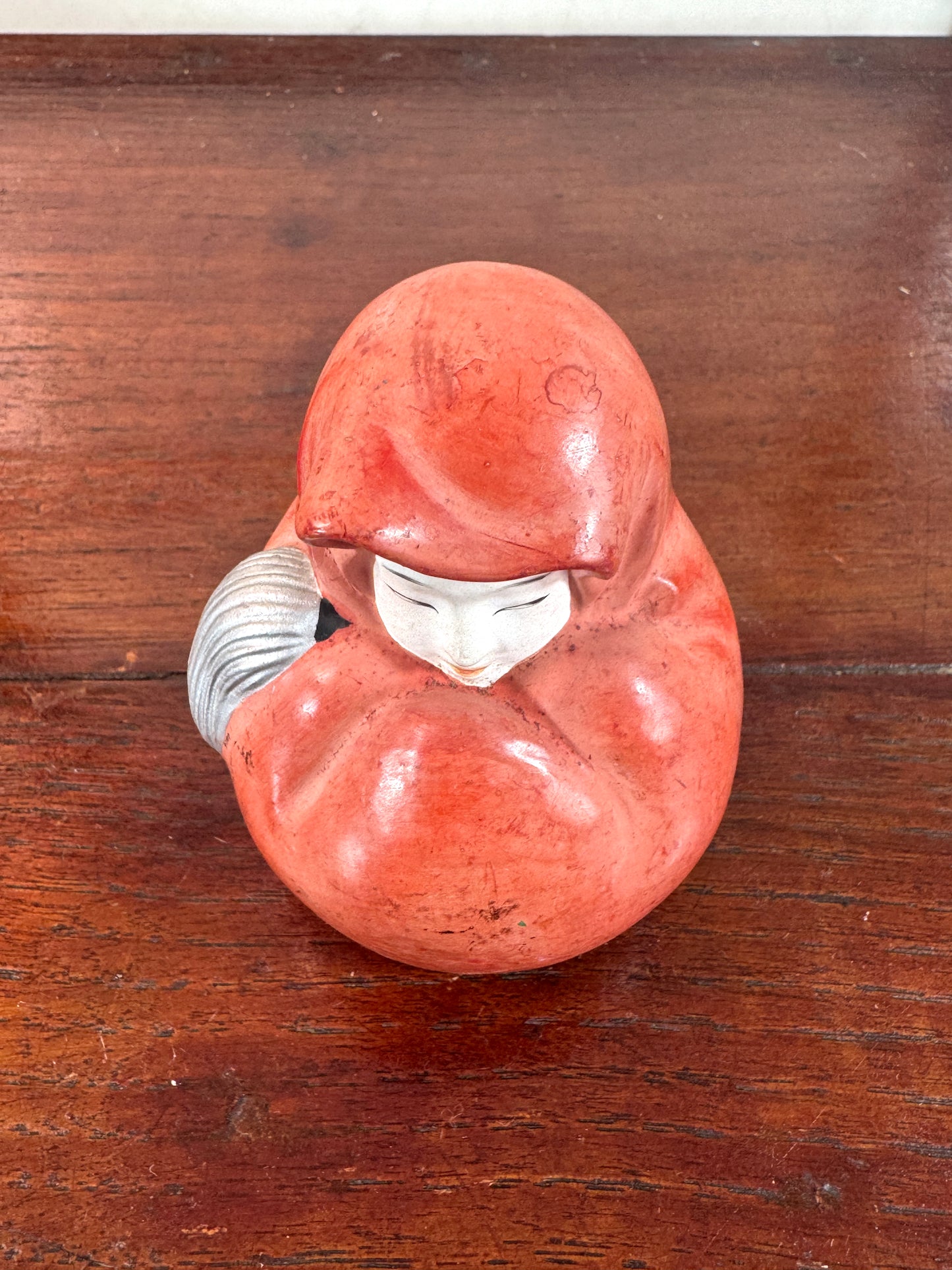 Statuette japonaise en céramique rouge représentant une princesse Daruma au visage délicat, vu de dessus