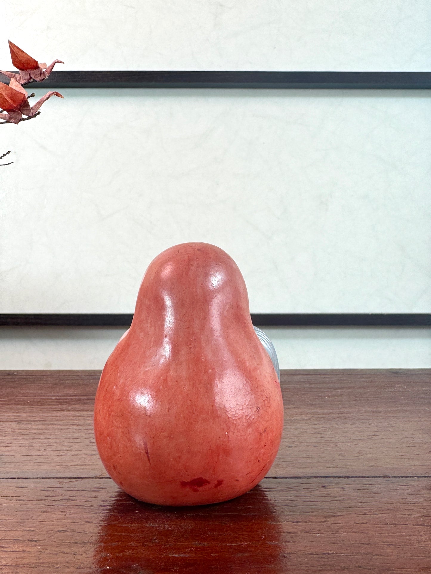 Statuette japonaise en céramique rouge représentant une princesse Daruma au visage délicat, vu de dos