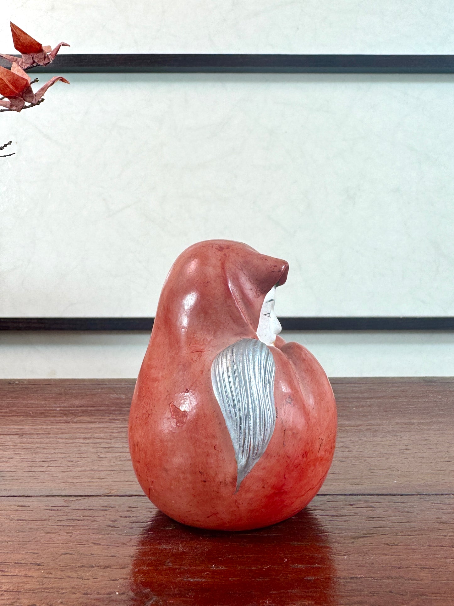 Statuette japonaise en céramique rouge représentant une princesse Daruma au visage délicat, vu du profil droit