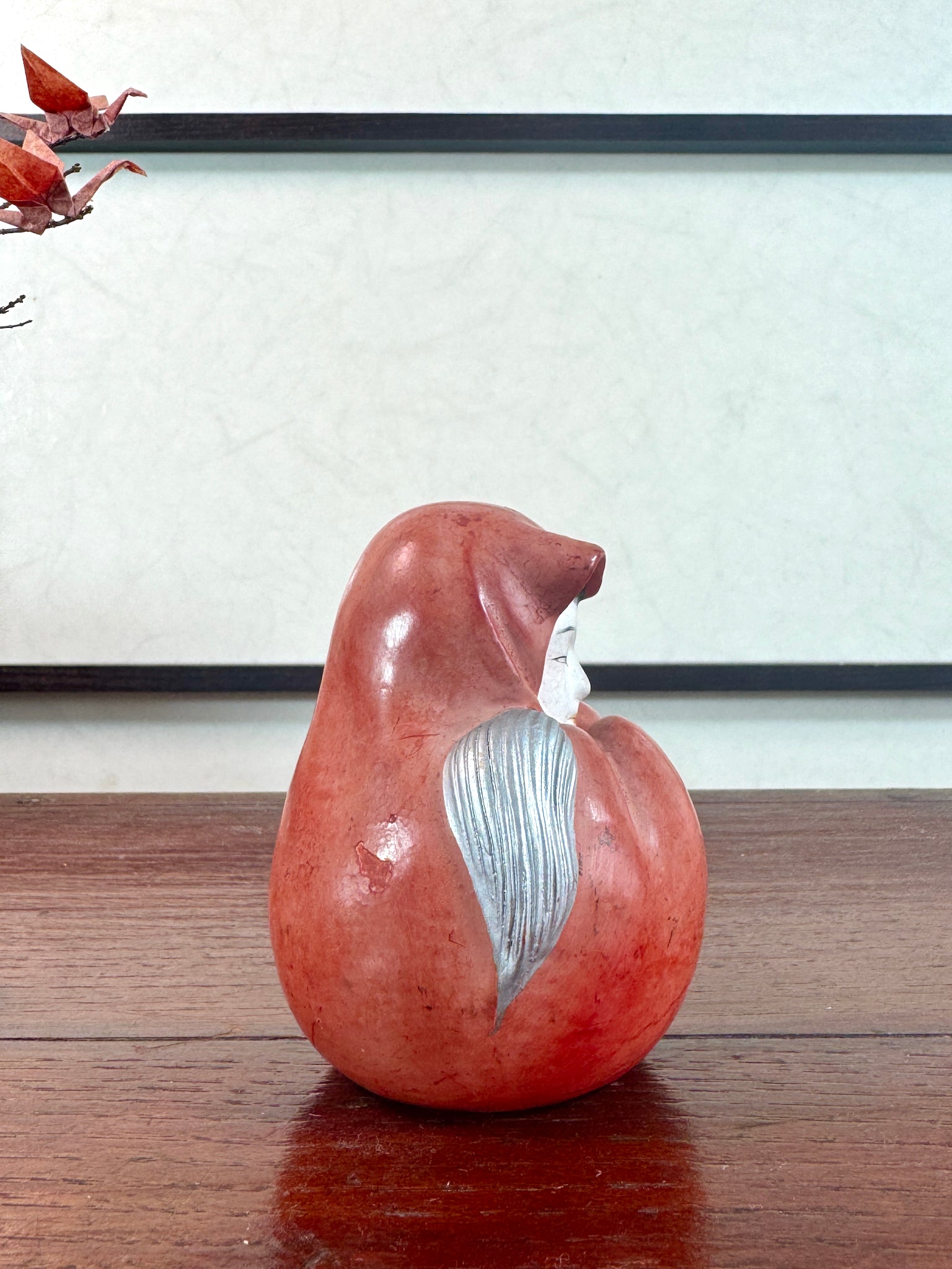 Statuette japonaise en céramique rouge représentant une princesse Daruma au visage délicat, vu du profil droit