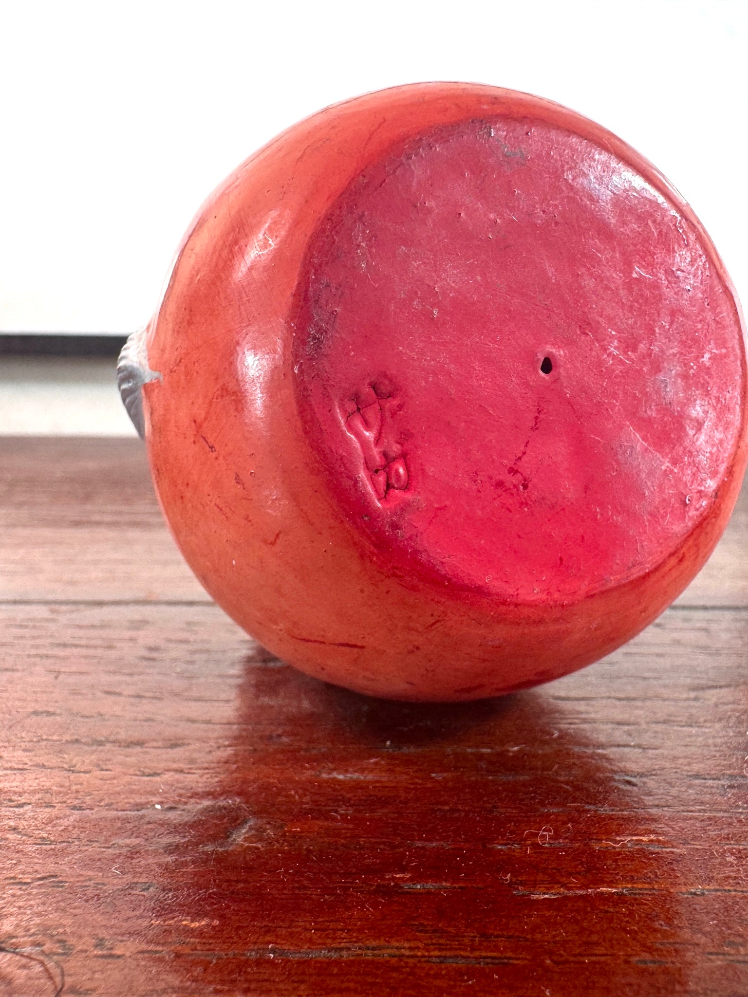 Statuette japonaise en céramique rouge représentant une princesse Daruma au visage délicat, vu de dessous avec le sceau de l'artisan