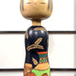 Kokeshi vintage de Yuji Kawase au corps noir décoré d’épis de riz et de deux récipients colorés à motifs géométriques, la vidéo à 360 degrés