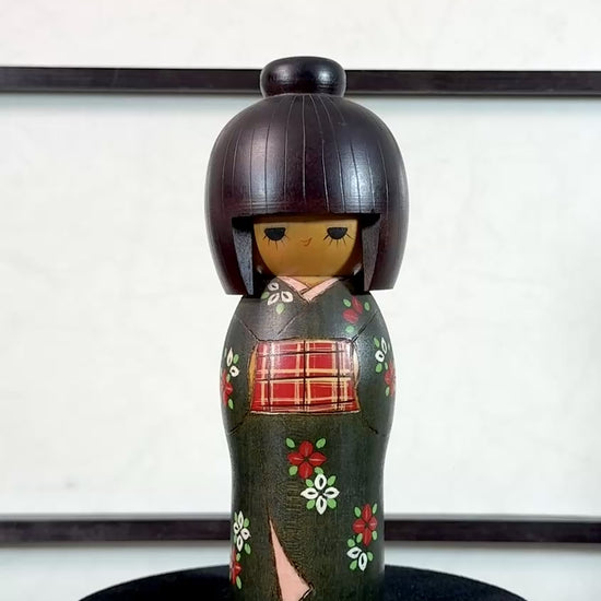 kokeshi gunma de Sadao Kishi au kimono vert, fleurs stylisées et obi rouge à carreaux, la vidéo de présentation à 360 degrés