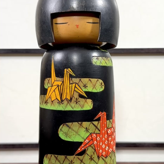 Kokeshi vintage de Yuji Kawase datée de 1992, décorée de grues en origami jaunes et rouges sur un corps noir., la vidéo à 360 degrés