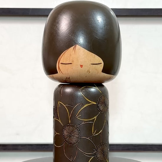 Kokeshi vintage de Yuji Kawase caractérisée par une grande tête brune, un corps étroit et un décor de fleurs gravées, la vidéo à 360 degrés