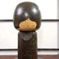 Kokeshi vintage de Yuji Kawase datée de 1980, caractérisée par une grande tête brune, un corps étroit et un décor de fleurs gravées, la vidéo