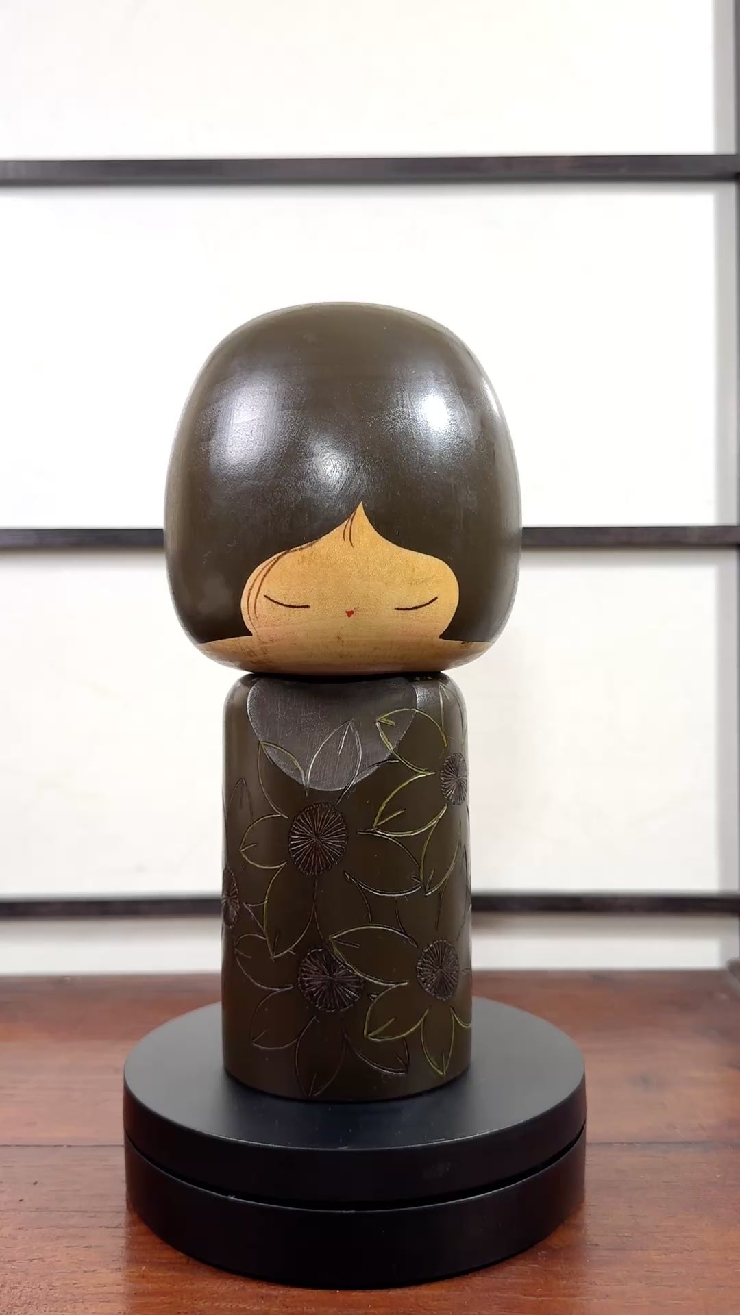 Kokeshi vintage de Yuji Kawase datée de 1980, caractérisée par une grande tête brune, un corps étroit et un décor de fleurs gravées, la vidéo