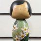 Kokeshi vintage de Yuji Kawase datée de 1994, au corps vert décoré de fleurs blanches et à la coiffure noire asymétrique, la vidéo à 360 degrés