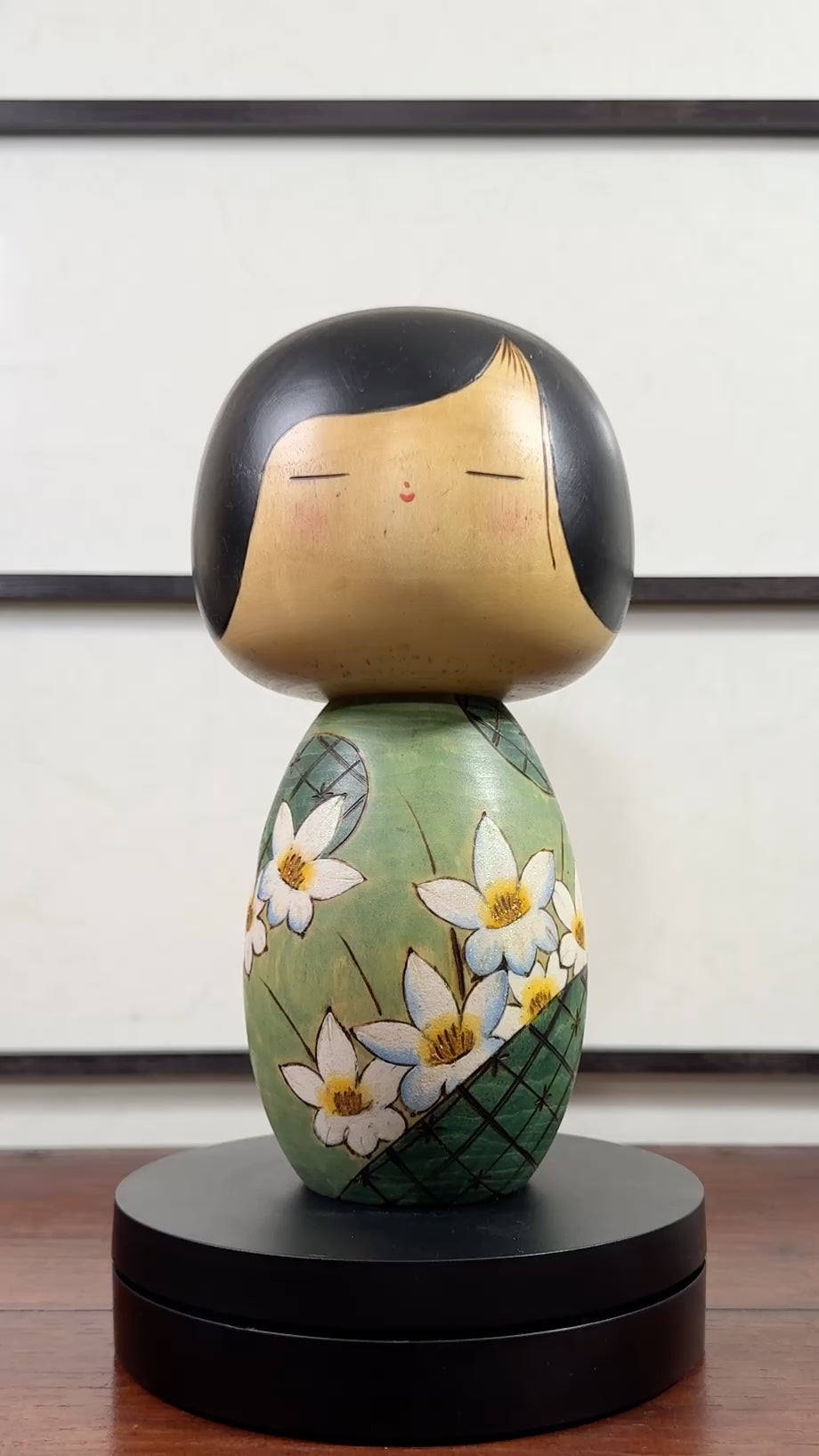 Kokeshi vintage de Yuji Kawase datée de 1994, au corps vert décoré de fleurs blanches et à la coiffure noire asymétrique, la vidéo à 360 degrés