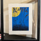 estampe japonaise contemporaine encadrée de Sano Takao, la pleine lune en automne avec herbes graminées en premier plan, entre-deux-verre et cadre noir, posé sur un meuble