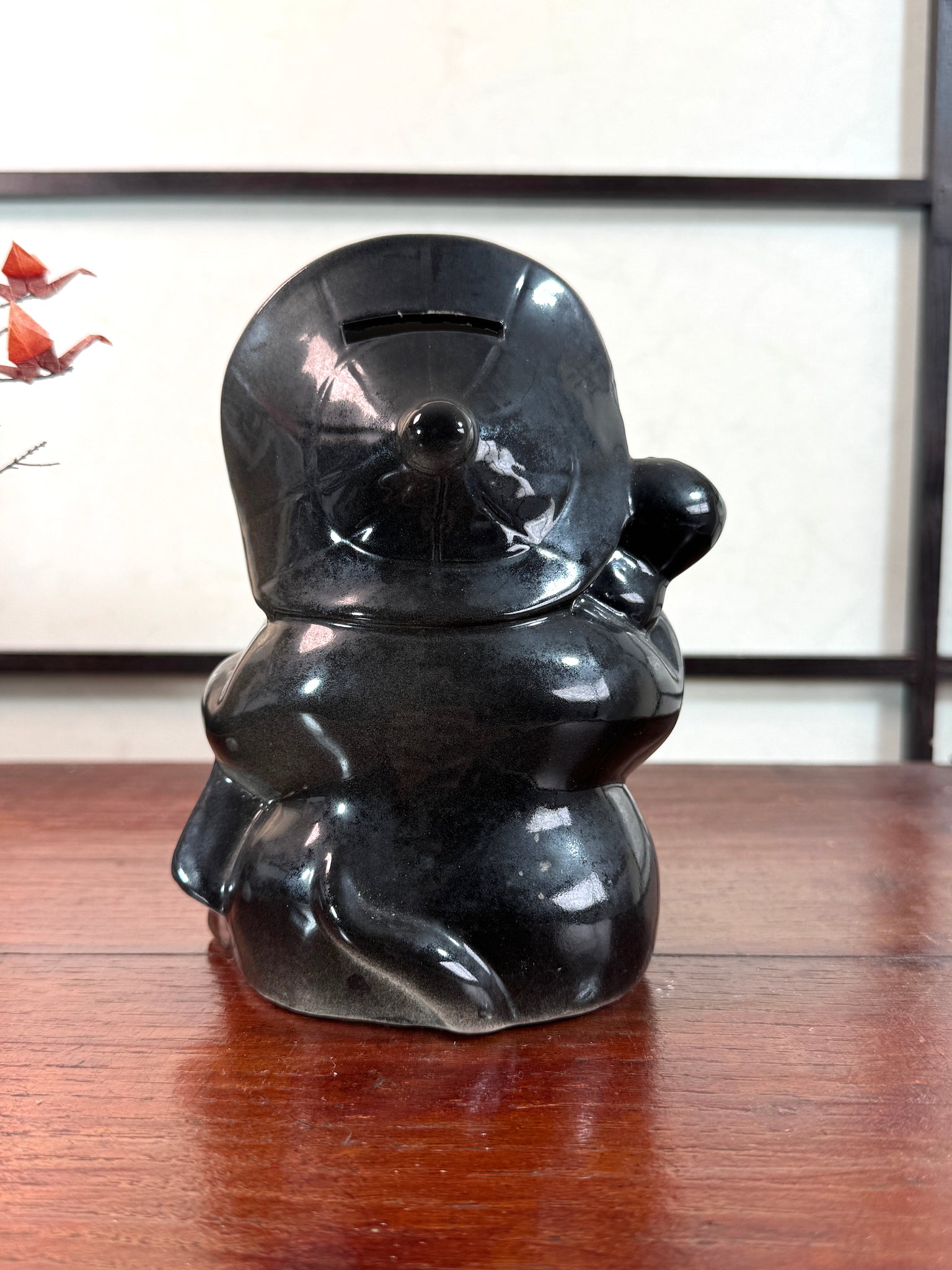 Tirelire tanuki en céramique émaillée noire et crème, style japonais traditionnel, vu de dos