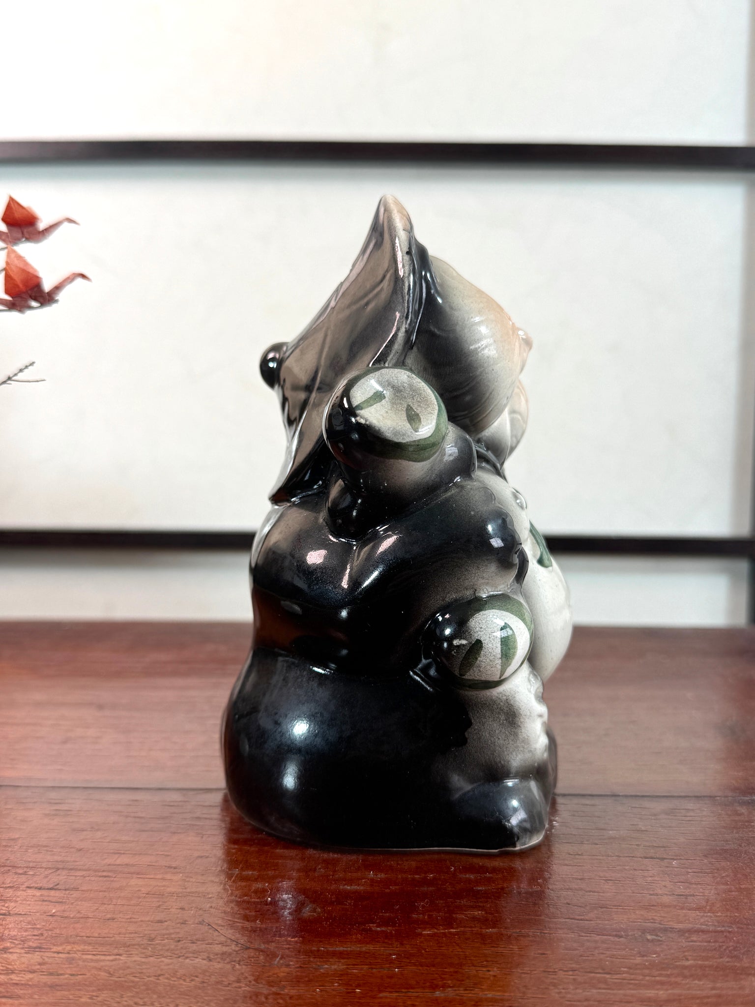 Tirelire tanuki en céramique émaillée noire et crème, style japonais traditionnel, vu du profil droit