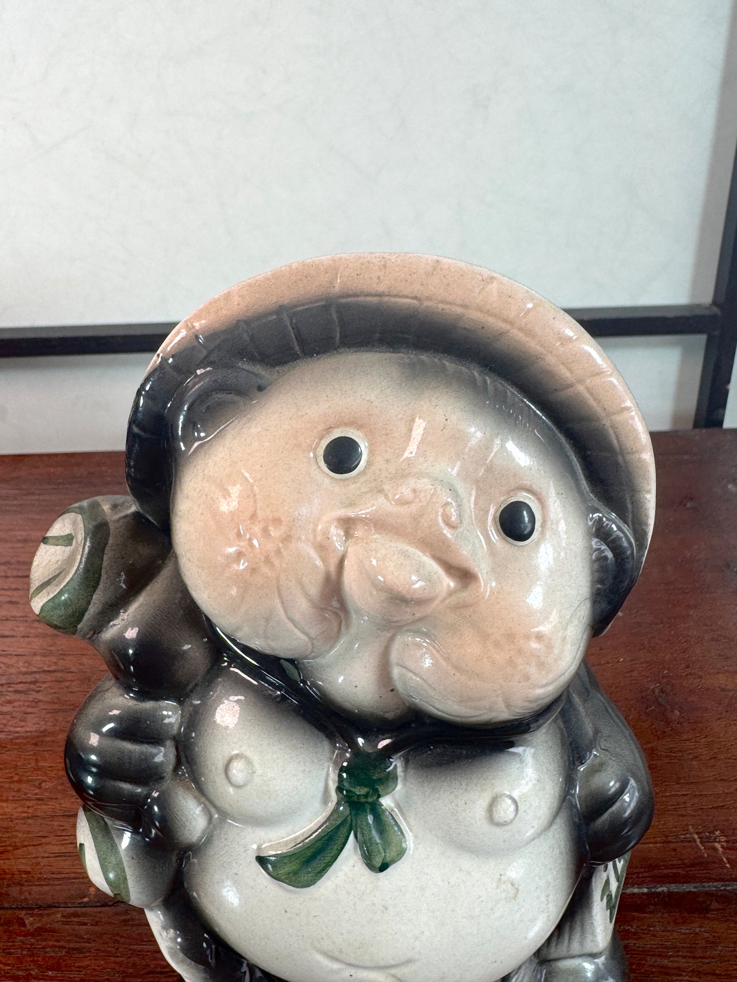 Tirelire tanuki en céramique émaillée noire et crème, style japonais traditionnel, gros plan sur le visage aux joues roses