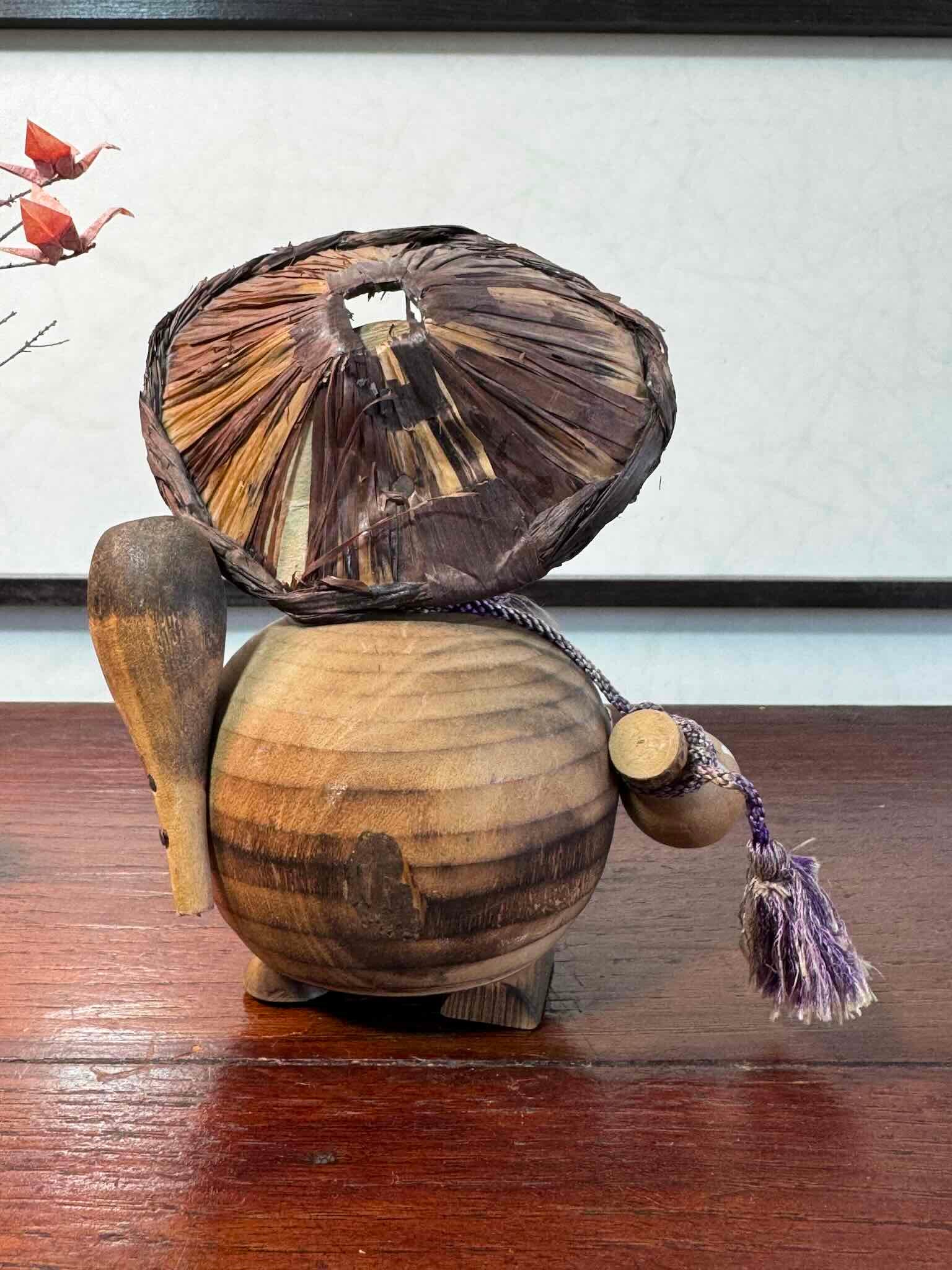 tanuki en bois avec son chapeau, bébé et sa bouteille de saké, vu de dos