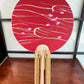 éventail japonais uchiwa rouge, des pétales de cerisier flottent sur l'eau, avec support bambou
