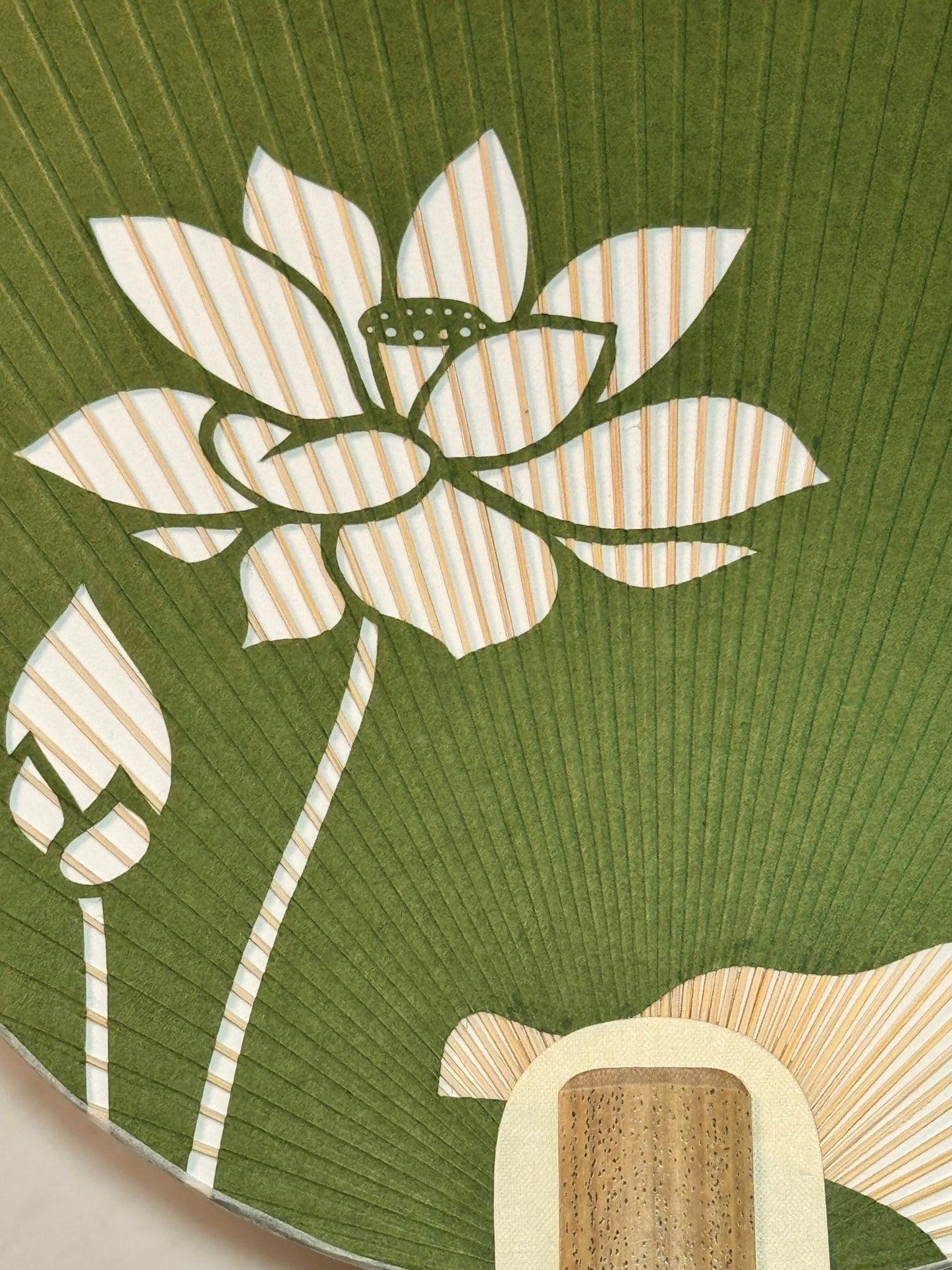 eventail Uchiwa vert avec fleur de lotus découpée, gros plan sur la fleur