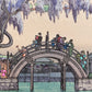 Taiko Bashi, pont japonais en demi-lune avec visiteurs venus admirer les glycines.