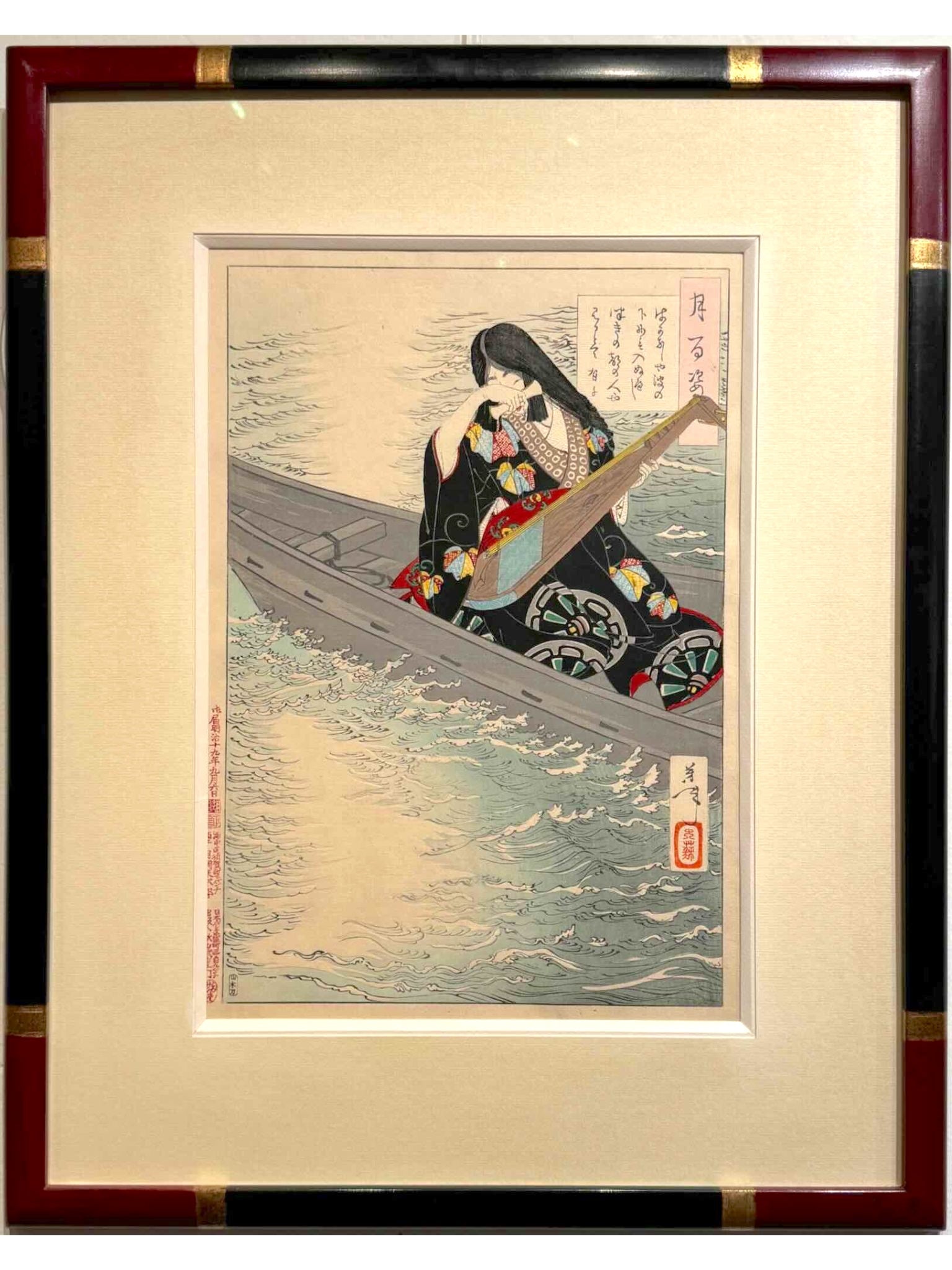 Estampe japonaise de yoshitoshi femme aux longs cheveux, en kimono noir à motif et obi rouge,  tenant un luth sur une barque, encadrée avec un cadre noir à angle rouge chine et bagues or
