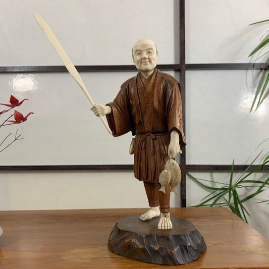 Okemono, statuette traditionnelle japonaise en bois et voir, pêcheur tant dans sa main des poissons